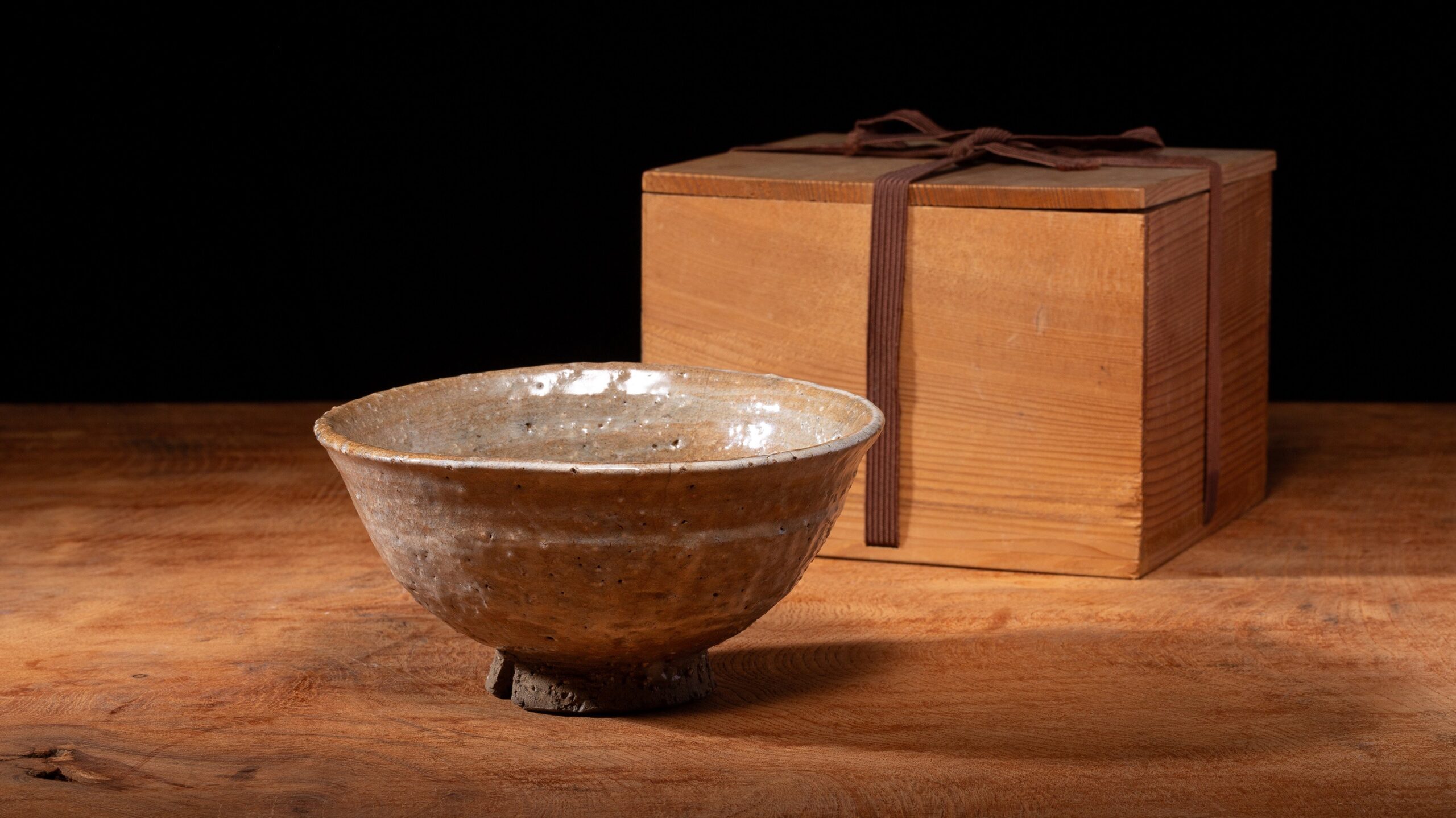 木箱の横に置かれた釉薬の風合いがある陶器の茶碗